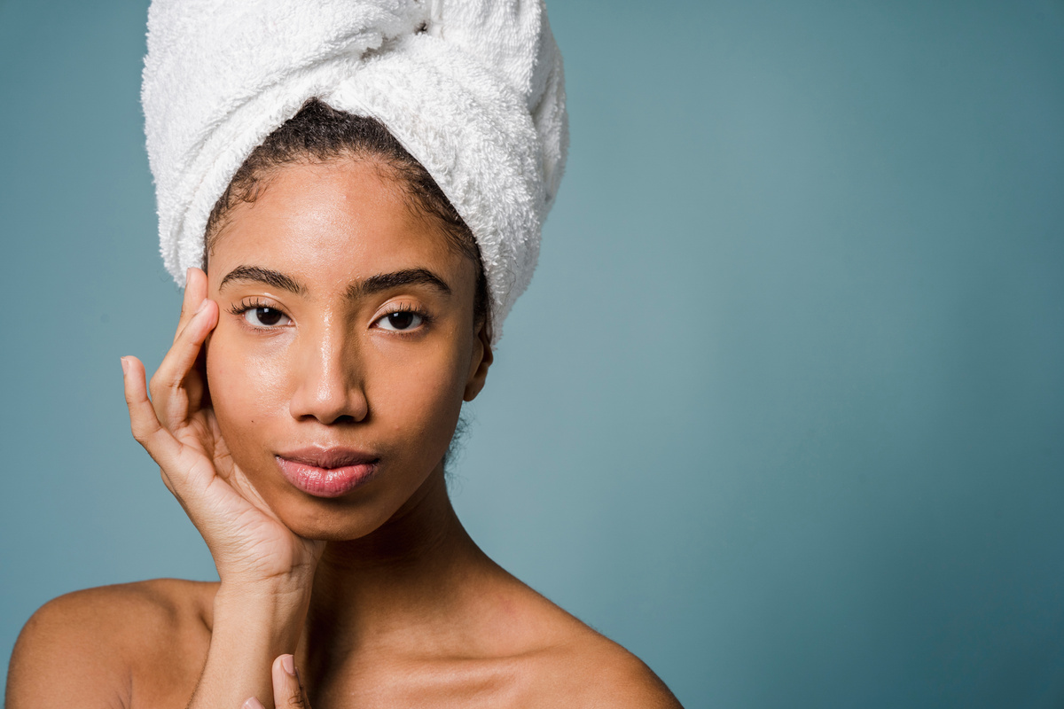 Calm young ethnic woman with perfect skin touching face after shower